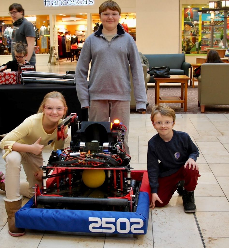 Three kids posing with the bot