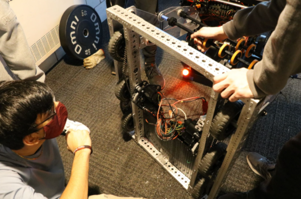 The robot shitting on the floor. A team member is inspecting the drive train.