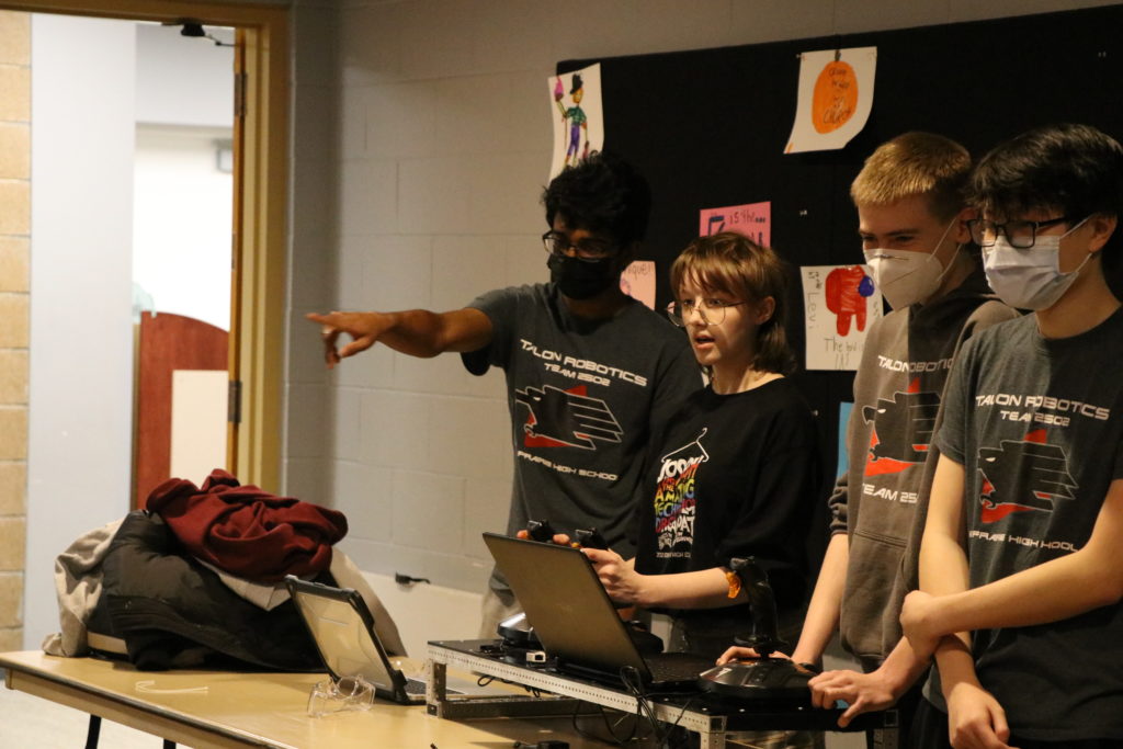 A student driving the robot with the drive team behind them.