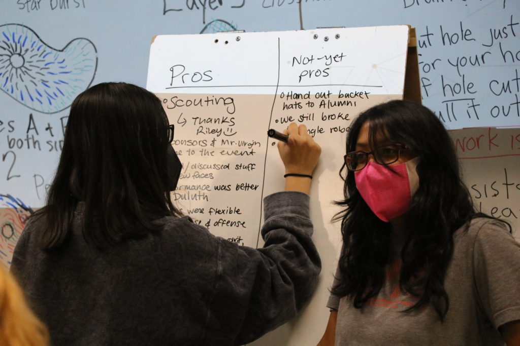 two students writing on a whiteboard