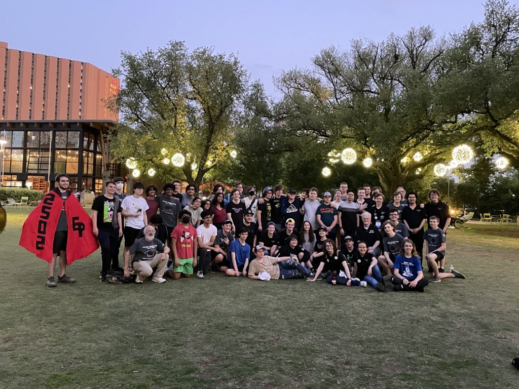 Both teams posing for a photo at the park.