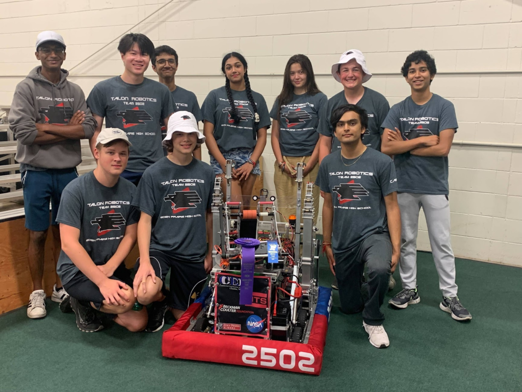 ten team members posing for a picture with the robot.