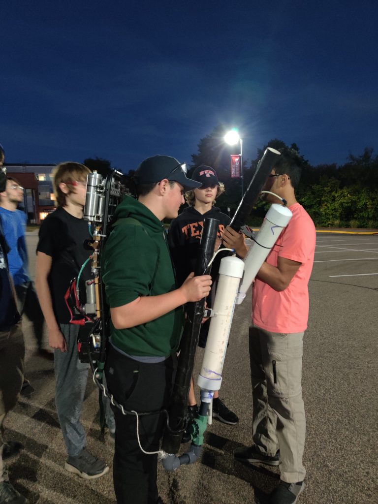 Multiple students loading the t-shirt cannon outside in a parking lot