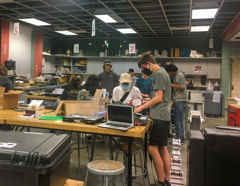 Multiple people working on tables in the robotics room.