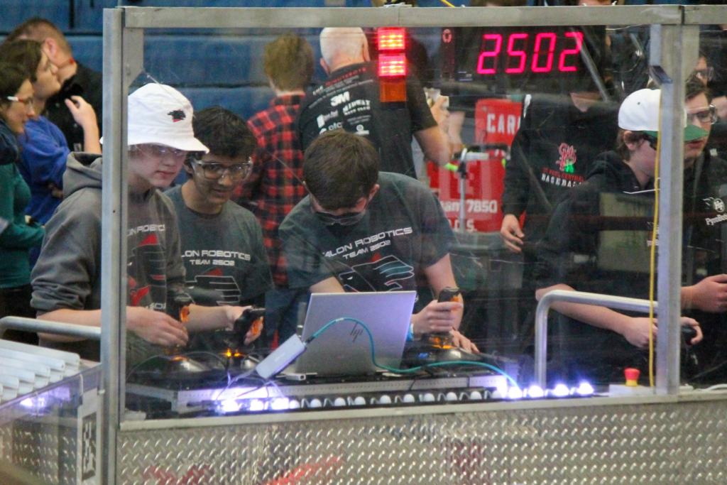 Three team members behind the safety glass controlling the robot.