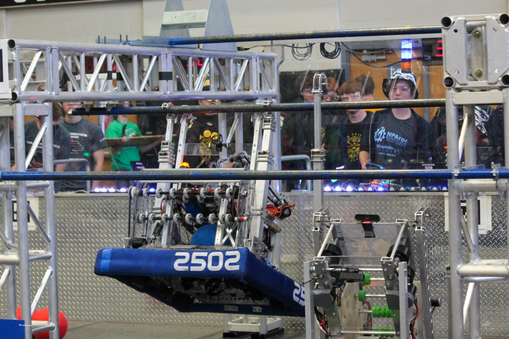 The robot climbing on the middle bar going up to the high bar in the blue hangar.