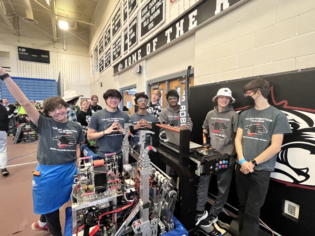 six team members posing for a photo next to our robot.