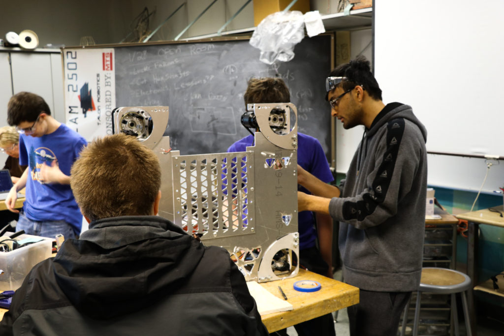 Multiple students working on the belly pan of the robot. 
