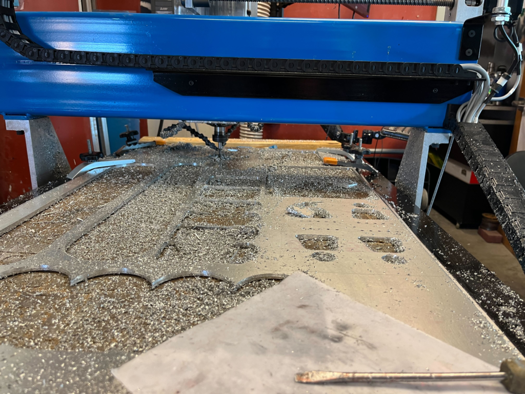 The CNC machine running at full force. there is an aluminum sheet that is being cut up. Metal shavings everywhere