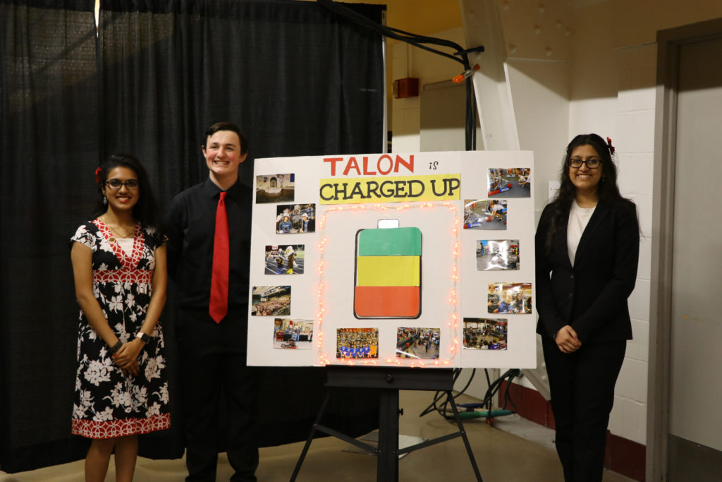 three team members posing in the front of their impact poster board.