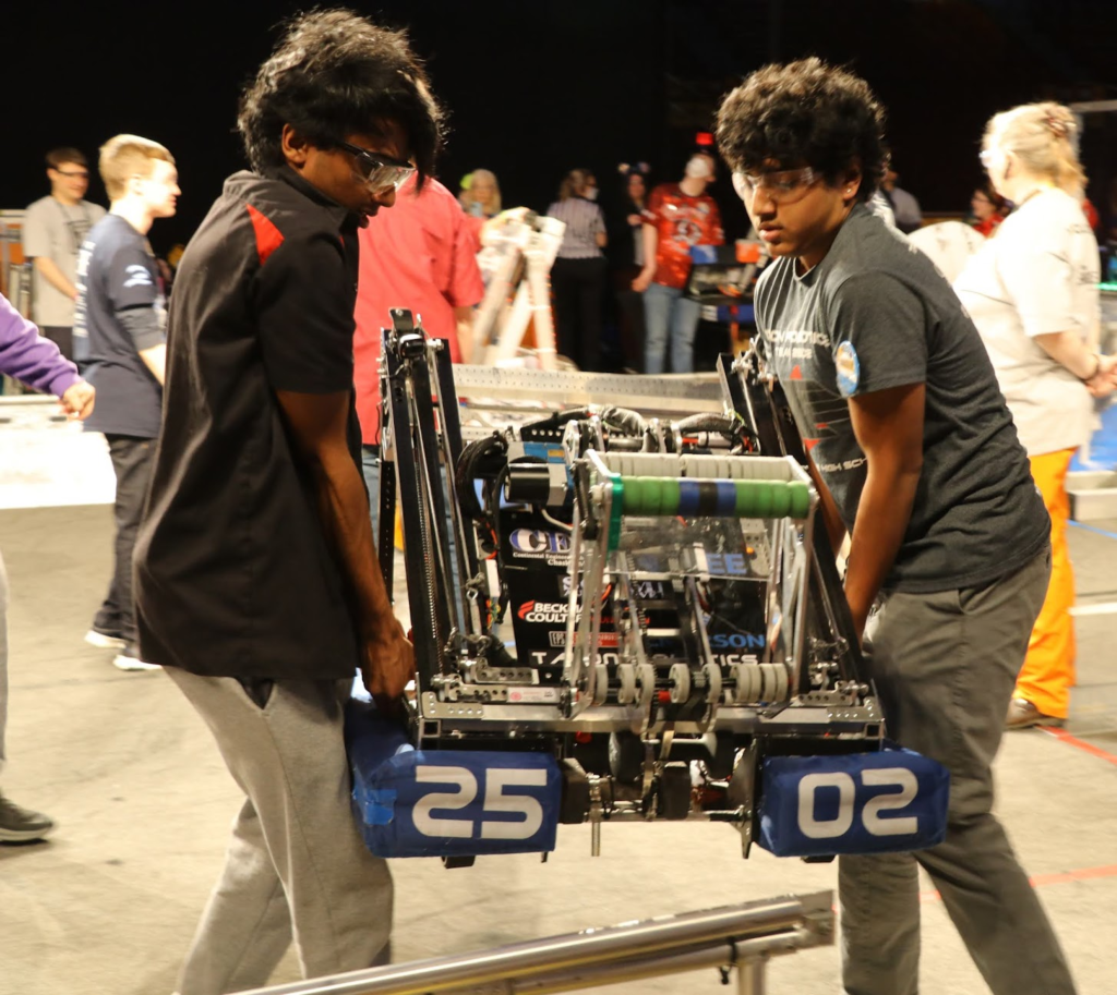 Two drive team members moving the robot off of the field
