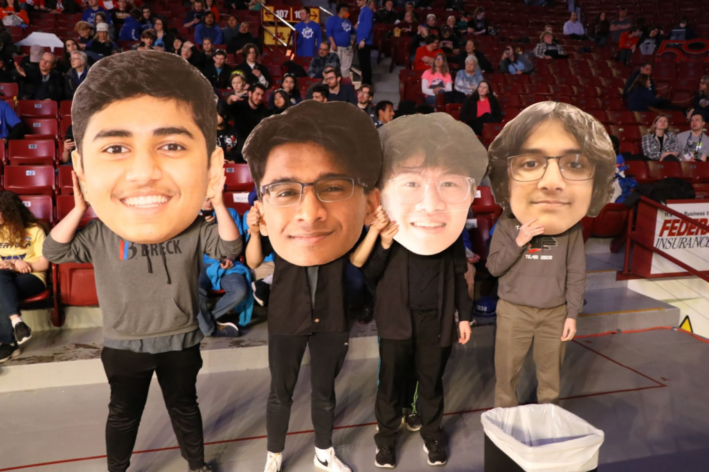 Four team members holding giant heads of the drive team. each one hold the heading is acting as if there are that person. 