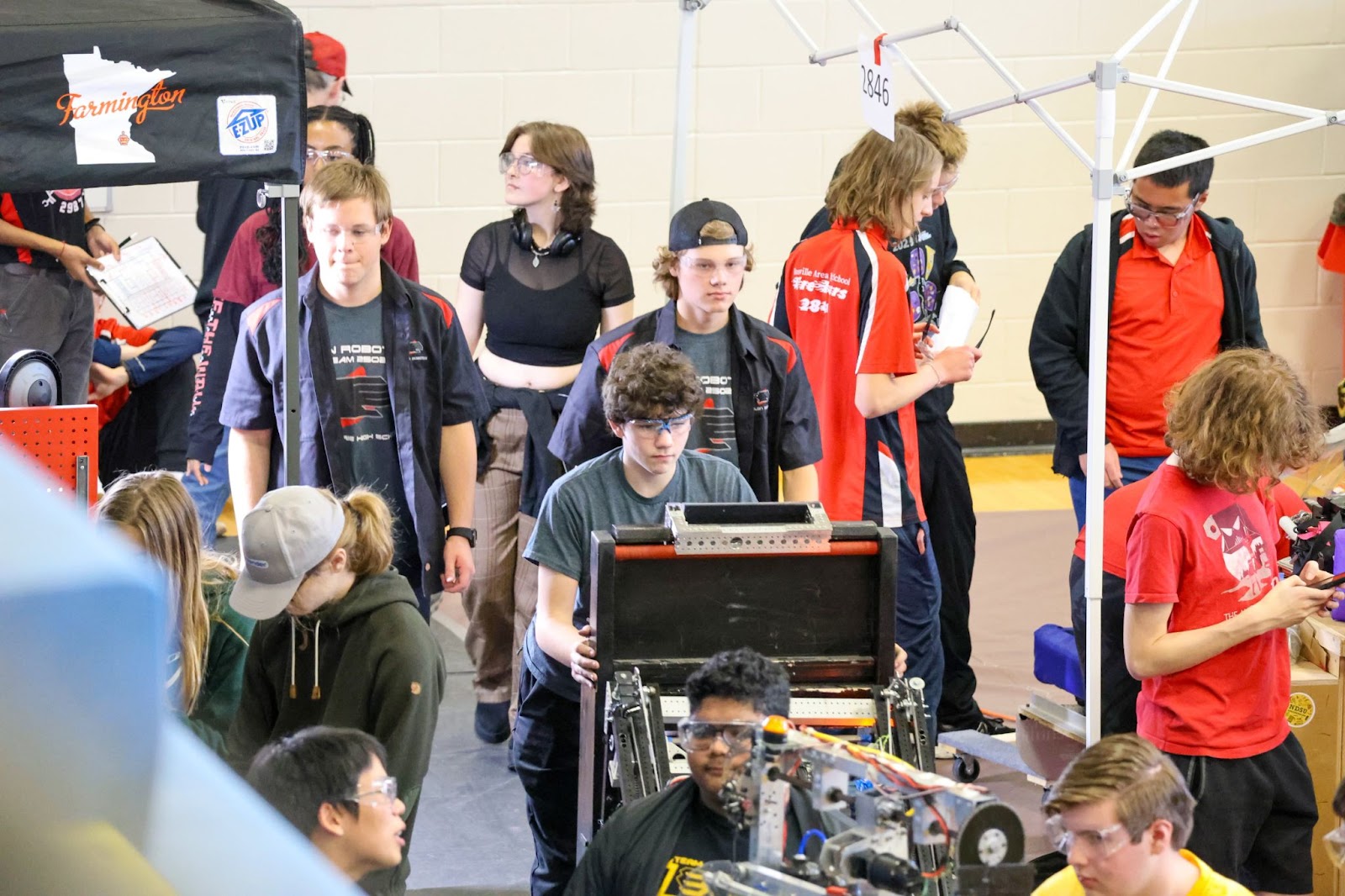 Three members of the drive team walking down the line in the pits with the robot cart