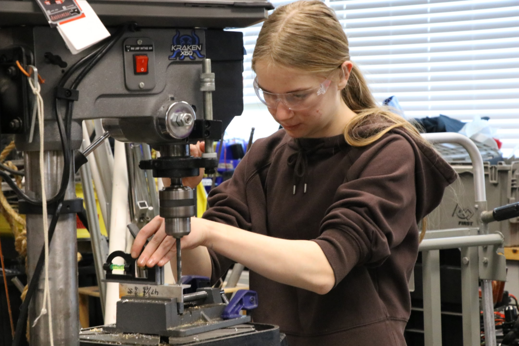 One student using a drill press with a level