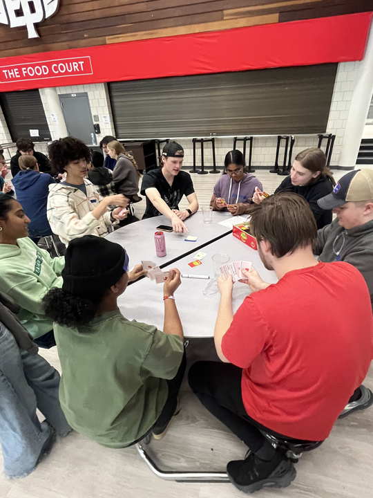 Team members from Talon and Stampede sitting around a table playing a game