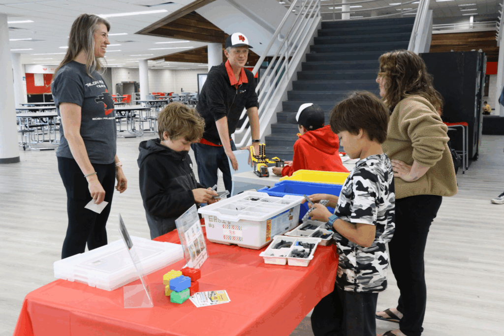 Kids standing around a lego building with lego bricks