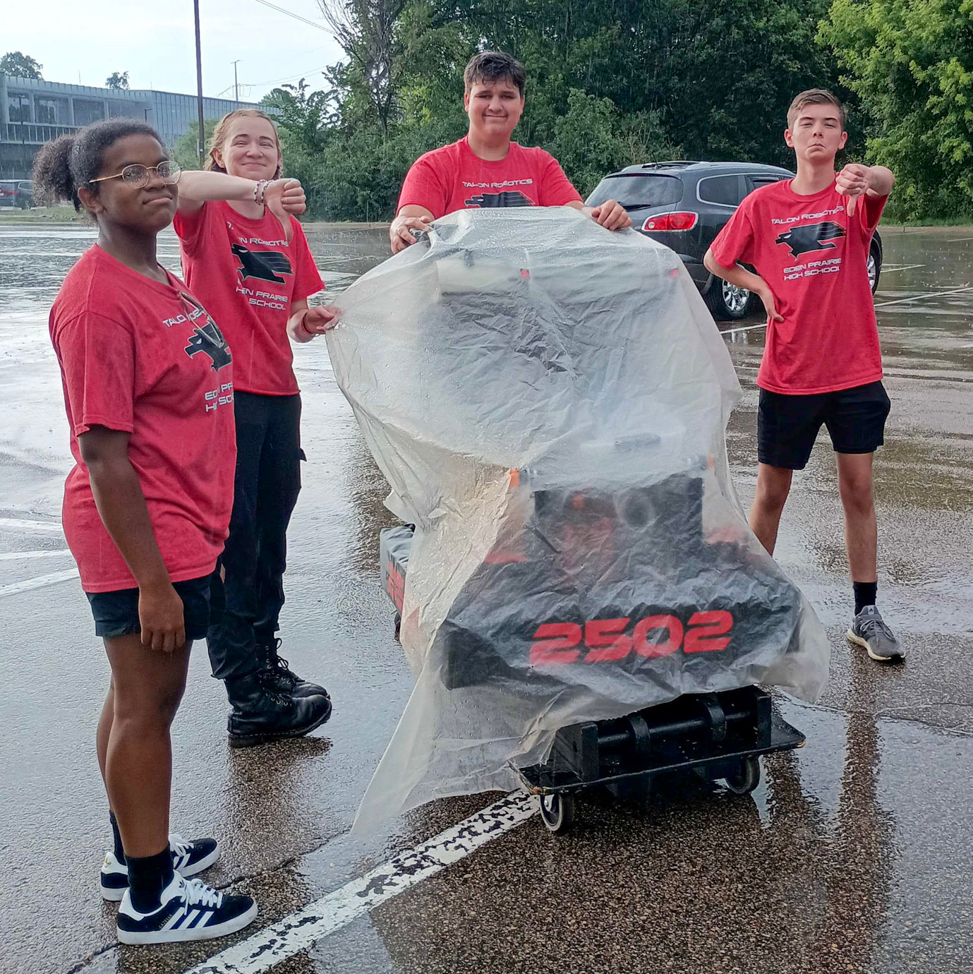 Team members frowning and giving thumbs down surrounding Lefty which is covered by a tarp