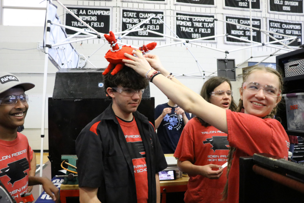 Ally putting our crab mascot, Ferris, on Timothy, her co captain