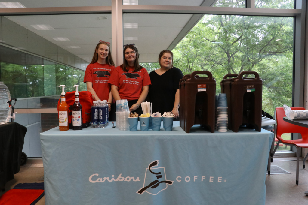 Charlotte and Ally posing with a representative from Caribou Coffee