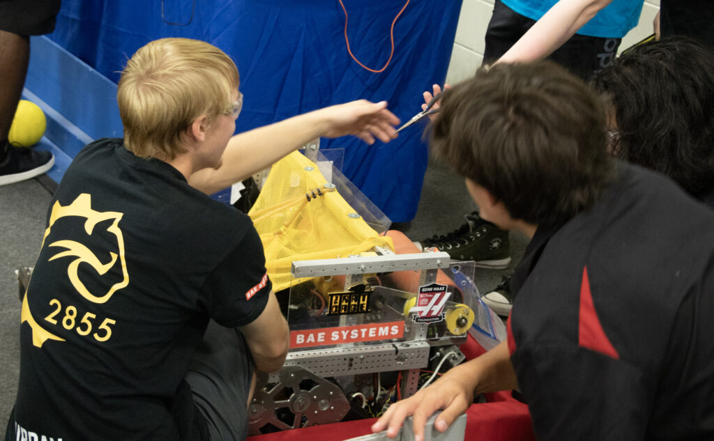 Image shows a beastbot member and a talon member working on a robot together at the fair